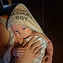 baby, towel, hood, mamas_boy, infant, hand, person, holding, skin, arm, indoor, wooden_wall, soft_lighting, curious, cozy, snug, portrait, closeup, child, warm