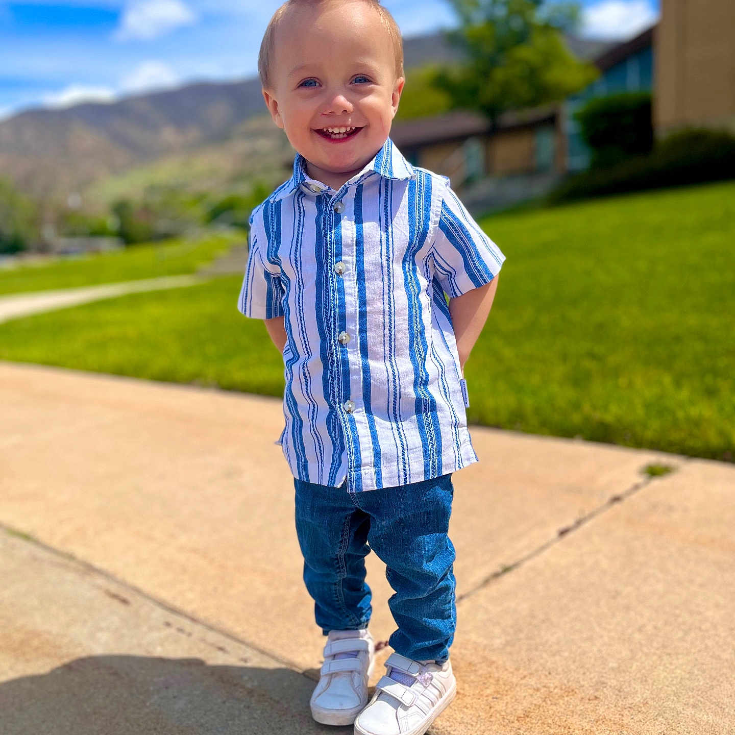 Alexander joined the competition — help win amazing prizes! child, boy, smiling, outdoor, sunny_day, blue_sky, clouds, grass, tree, mountains, sidewalk, shirt, jeans, sneakers, happy, portrait, casual_clothing, standing, hair, daylight