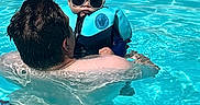 Alexander is registered to the contest to win money with this photo: adult, baby, blue, child, cool, family, floatation_vest, fun, leisure, outdoor, parent, person, pool, safety, summer, sunglasses, sunlight, swimming, vacation, water