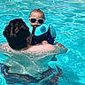 Alexander is registered to the contest to win money with this photo: baby, child, adult, pool, water, sunglasses, floatation_vest, swimming, summer, outdoor, person, blue, cool, vacation, fun, leisure, parent, family, sunlight, safety