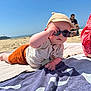 baby, beach, sunglasses, cap, towel, sand, sunny, child, outdoor, summer, relaxing, person, clothing, infant, accessory, vacation, casual, reclining, headwear, sunshine
