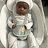baby, infant, child, portrait, bouncer, baby_seat, hat, beanie, striped_outfit, harness, plush_toy, owl_toy, slippers, animal_slippers, cushion, blanket, indoors, sitting, serious_expression, safe_sleep_space
