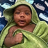 Jaevion is registered to the contest to win money with this photo: newborn, baby, infant, child, portrait, face, eyes, smiling, hooded_towel, green_towel, thumbs_up, lying_down, blanket, whale_pattern, bedding, indoors, close_up, relaxed, cozy, photography