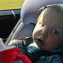 toddler, child, car_seat, sippy_cup, seatbelt, blue_shirt, sunlight, shadow, car_interior, hand, face, window, outdoor, nature, greenery, hair_clip, expression, portrait, travel, safety