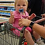 Emma Pauline is registered to the contest to win money with this photo: toddler, child, shopping_cart, pacifier, grocery_store, adult, person, pink_clothing, sneakers, socks, beard, hat, shopping, aisle, products, hand, floor, metal, cart_handle, casual
