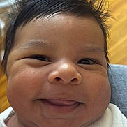 Jussuf is registered to the contest to win money with this photo: baby, smiling, close_up, face, hair, spiky_hair, onesie, white_clothing, infant, cute, happy, child, portrait, skin, indoors, person, young, expression, cheeks, button