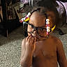 Jasamira is registered to the contest to win money with this photo: toddler, child, glasses, beads, hair, indoor, carpet, curious, shirtless, person, face, hand, young_child, home, floor, expression, portrait, cute, baby, room