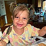 toddler, child, smiling, breakfast, cereal, milk, kitchen, spoon, pigtails, hair, clothing, table, highchair, wooden_furniture, indoors, happy, face, person, food, meal