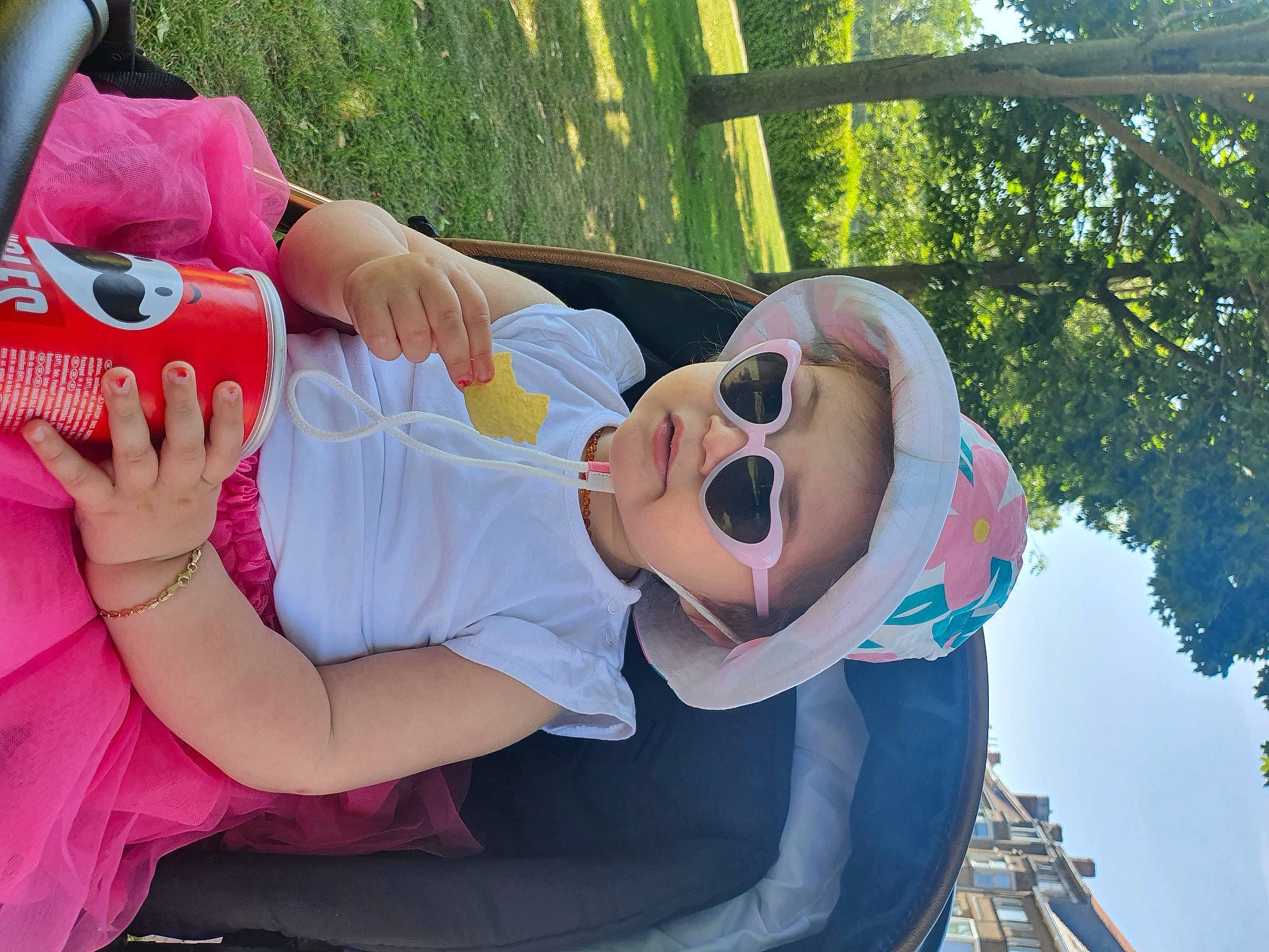 Erina participe au concours pour gagner de l'argent avec cette photo : child, event, eyewear, fun, gesture, grass, happy, hat, leisure, mouth, person, pink, recreation, sandal, sitting, spring, sunglasses, toddler, toy, tree