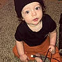 Yz Hezekiah is registered to the contest to win money with this photo: toddler, child, carpet, indoor, beanie, black_shirt, orange_pants, usb_cable, curly_hair, blue_eyes, sitting, floor, technology, cute, baby, person, young_child, candid, home, curious