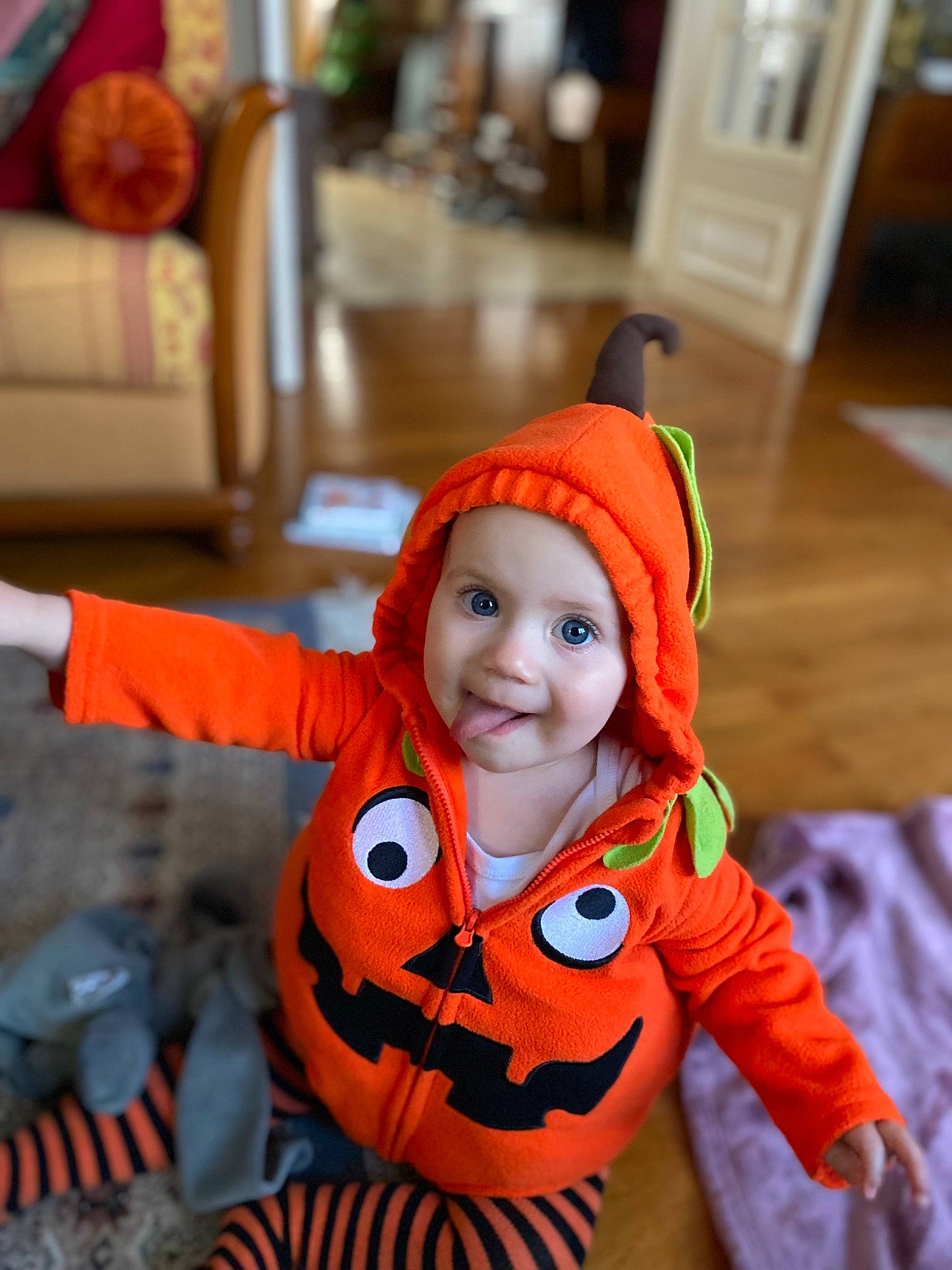 Jeanne participe au concours pour gagner de l'argent avec cette photo : baby, baby_toddler_clothing, calabaza, flooring, fun, glove, gourd, happy, headwear, human_body, jack_o_lantern, leisure, orange, person, personal_protective_equipment, pumpkin, sitting, smile, toddler, tree