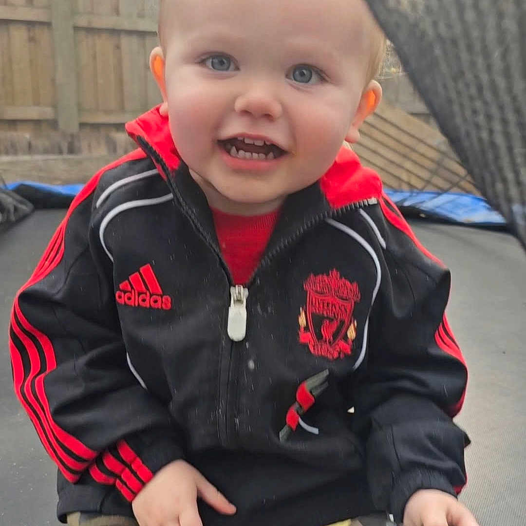 Lewie joined the competition — help win amazing prizes! adidas, black, blonde, blue_eyes, bottle, casual, child, clothing, face, fence, happy, jacket, outdoor, person, playtime, red, sitting, smiling, sportswear, toddler