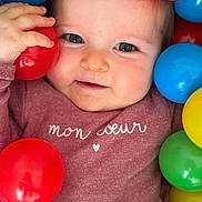 Talya a rejoint le concours — aidez-le/la à gagner de superbes lots ! baby, blue_ball, child, closeup, clothing, cute, eyes, face, green_ball, hand, indoor, infant, maroon, person, plastic_ball, playful, portrait, red_ball, smile, yellow_ball