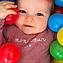 baby, blue_ball, child, closeup, clothing, cute, eyes, face, green_ball, hand, indoor, infant, maroon, person, plastic_ball, playful, portrait, red_ball, smile, yellow_ball