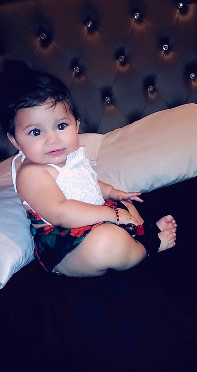 Chantal is registered to the contest to win money with this photo: arm, baby, beauty, cheek, child, eye, face, finger, hand, head, human_body, joint, leg, lip, nose, person, pink, sitting, skin, smile