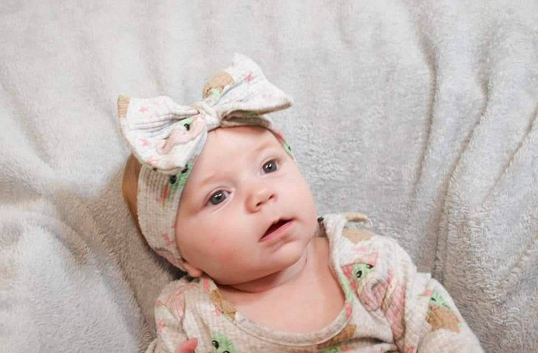 Alora is registered to the contest to win money with this photo: baby, baby_toddler_clothing, cheek, chin, embellishment, eye, eyebrow, eyelash, face, fashion_accessory, hair_accessory, happy, head, headpiece, headwear, iris, lip, nose, person, skin