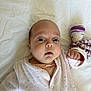 baby, infant, face, eyes, hand, onesie, clothing, bed, sheet, knitted_toy, purple, white, soft_toy, newborn, cute, child, portrait, lying_down, indoors, skin