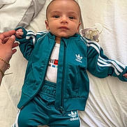 Islem a rejoint le concours — aidez-le/la à gagner de superbes lots ! baby, child, infant, adidas, tracksuit, blue_clothing, pacifier, hand, bed, blanket, person, face, lying_down, holding_hand, indoor, cute, young, apparel, human, portrait