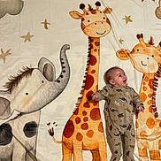 Lyam a rejoint le concours — aidez-le/la à gagner de superbes lots ! baby, infant, blanket, giraffe, elephant, cartoon, animal_print, dinosaur_onesie, smiling, child, cute, lying_down, playful, nursery, stars, soft_texture, happy, indoors, colorful, young