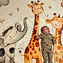 baby, infant, blanket, giraffe, elephant, cartoon, animal_print, dinosaur_onesie, smiling, child, cute, lying_down, playful, nursery, stars, soft_texture, happy, indoors, colorful, young