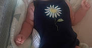 Ora is registered to the contest to win money with this photo: baby, onesie, daisy, crib, blanket, mesh, infant, child, sleeping_area, soft_toy, comfort, cute, calm, indoors, portrait, skin, face, arm, leg, resting