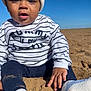 James joined the competition — help win amazing prizes! toddler, child, beach, sand, sweater, hat, sock, blue_sky, outdoor, sunny, portrait, casual_clothing, sitting, young_child, face, hand, footwear, closeup, cute, daytime