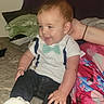 Owen is registered to the contest to win money with this photo: baby, child, infant, smiling, happy, portrait, sitting, bed, bedroom, indoor, bow_tie, shirt, suspenders, jeans, sneakers, clothing, pillow, blanket, adult_arm, cozy