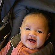 Audrey a rejoint le concours — aidez-le/la à gagner de superbes lots ! baby, child, smile, happy, face, jacket, pink, fleece, stroller, car_seat, straps, infant, cute, cheerful, portrait, indoors, person, young, head, clothing