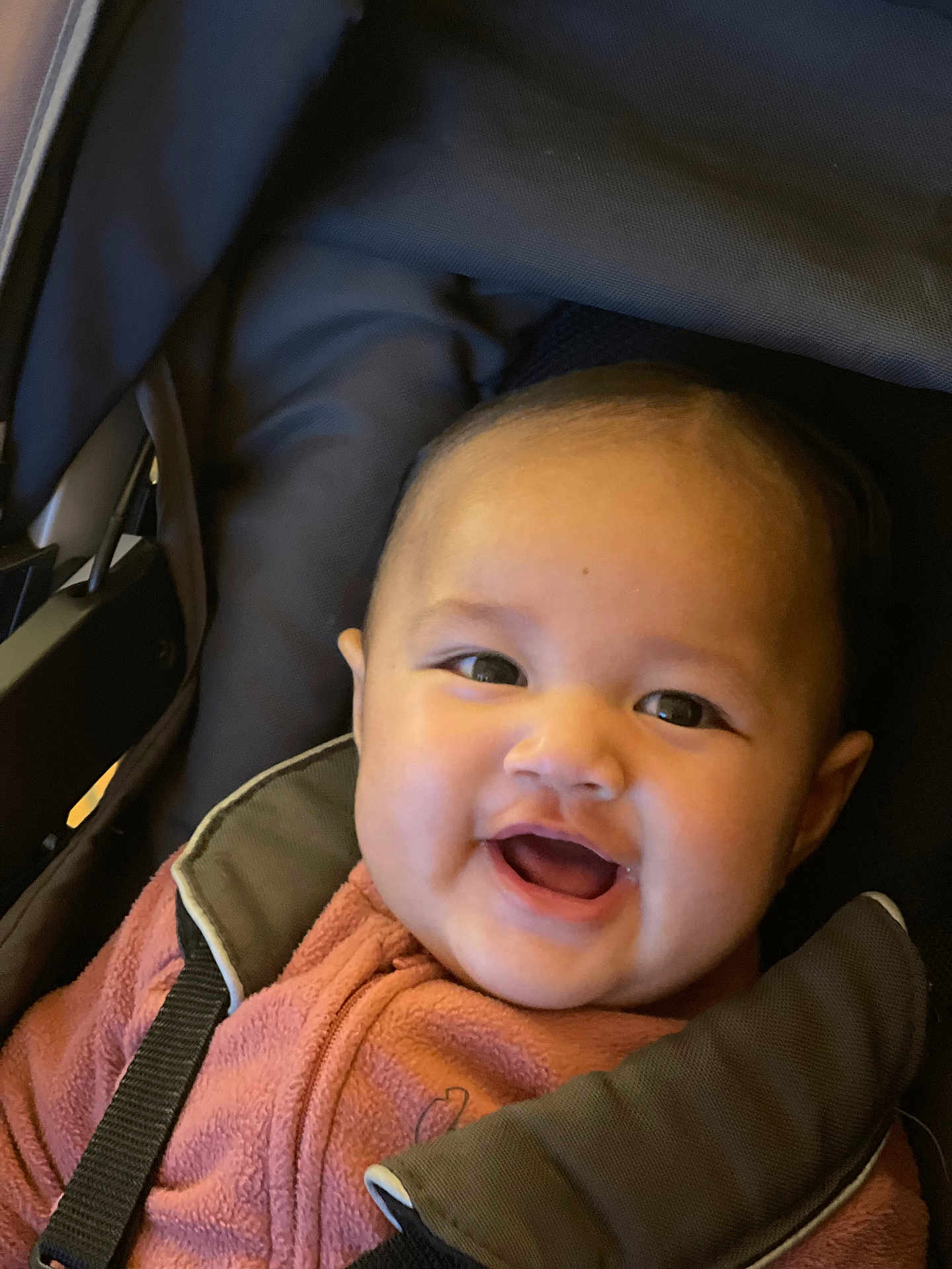 Audrey a rejoint le concours — aidez-le/la à gagner de superbes lots ! baby, child, smile, happy, face, jacket, pink, fleece, stroller, car_seat, straps, infant, cute, cheerful, portrait, indoors, person, young, head, clothing