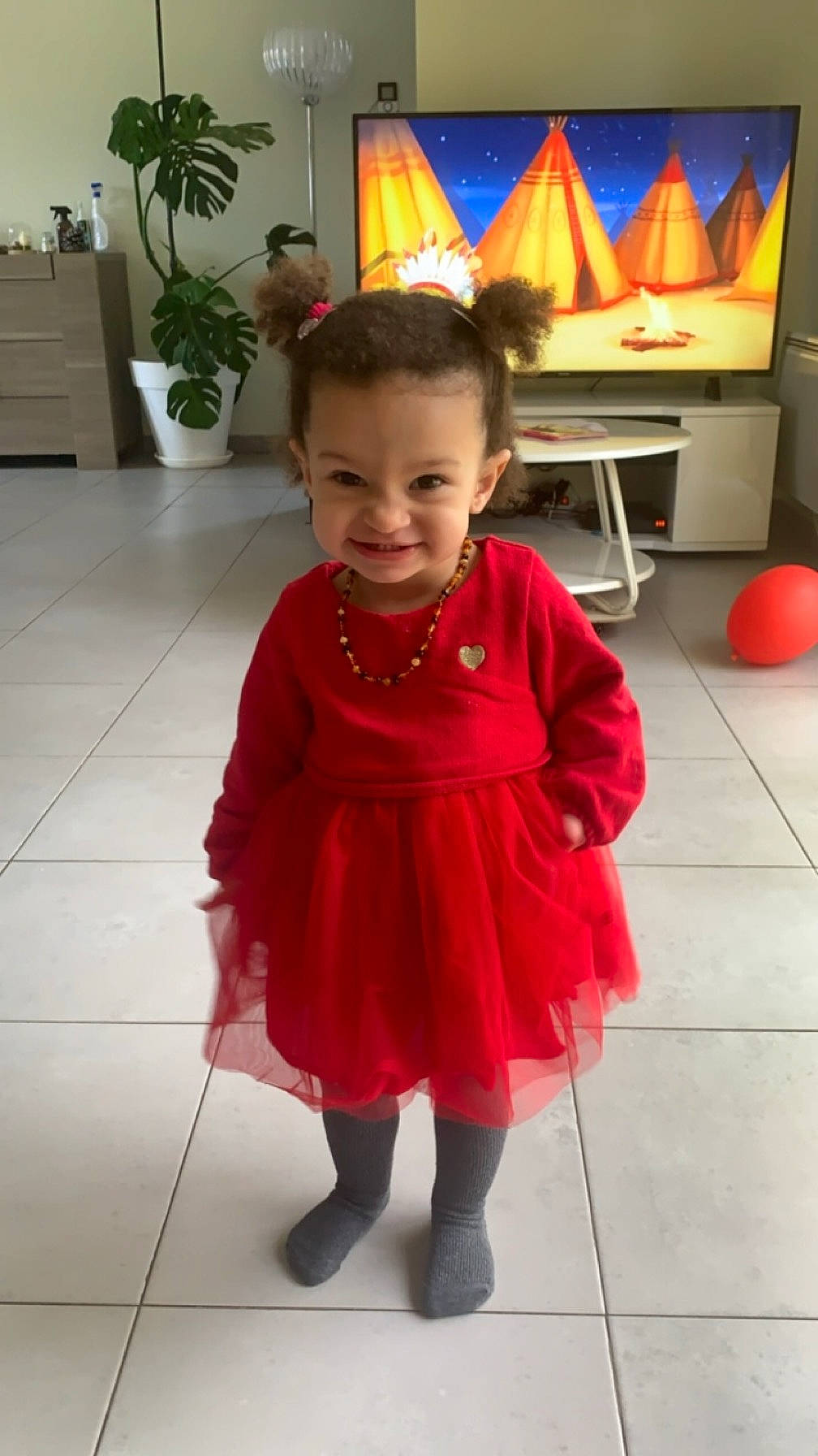 Leïa participe au concours pour gagner de l'argent avec cette photo : baby_toddler_clothing, dress, event, floor, flooring, flowerpot, fun, hair, head, houseplant, human_body, human_leg, joy, magenta, person, picture_frame, plant, skin, sleeve, smile