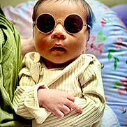 Zillion P Dorji is registered to the contest to win money with this photo: baby, sunglasses, infant, clothing, hand, face, person, cute, portrait, sitting, indoor, cozy, sleeve, fashion, young, child, resting, soft, cushion, colorful