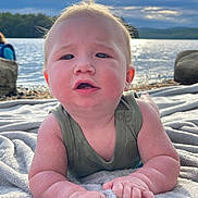 Grayson joined the competition — help win amazing prizes! baby, infant, blanket, water, lake, sky, clouds, sunlight, nature, outdoor, child, face, arms, expression, curious, green_clothing, rocks, scenery, portrait, relaxing
