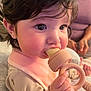 Lilith Sorrow joined the competition — help win amazing prizes! baby, child, teething_toy, pink_bib, pajamas, hand, face, chewing, close_up, indoor, person, soft_lighting, curly_hair, cute, infant, holding, skin, expression, young_child, blurred_background