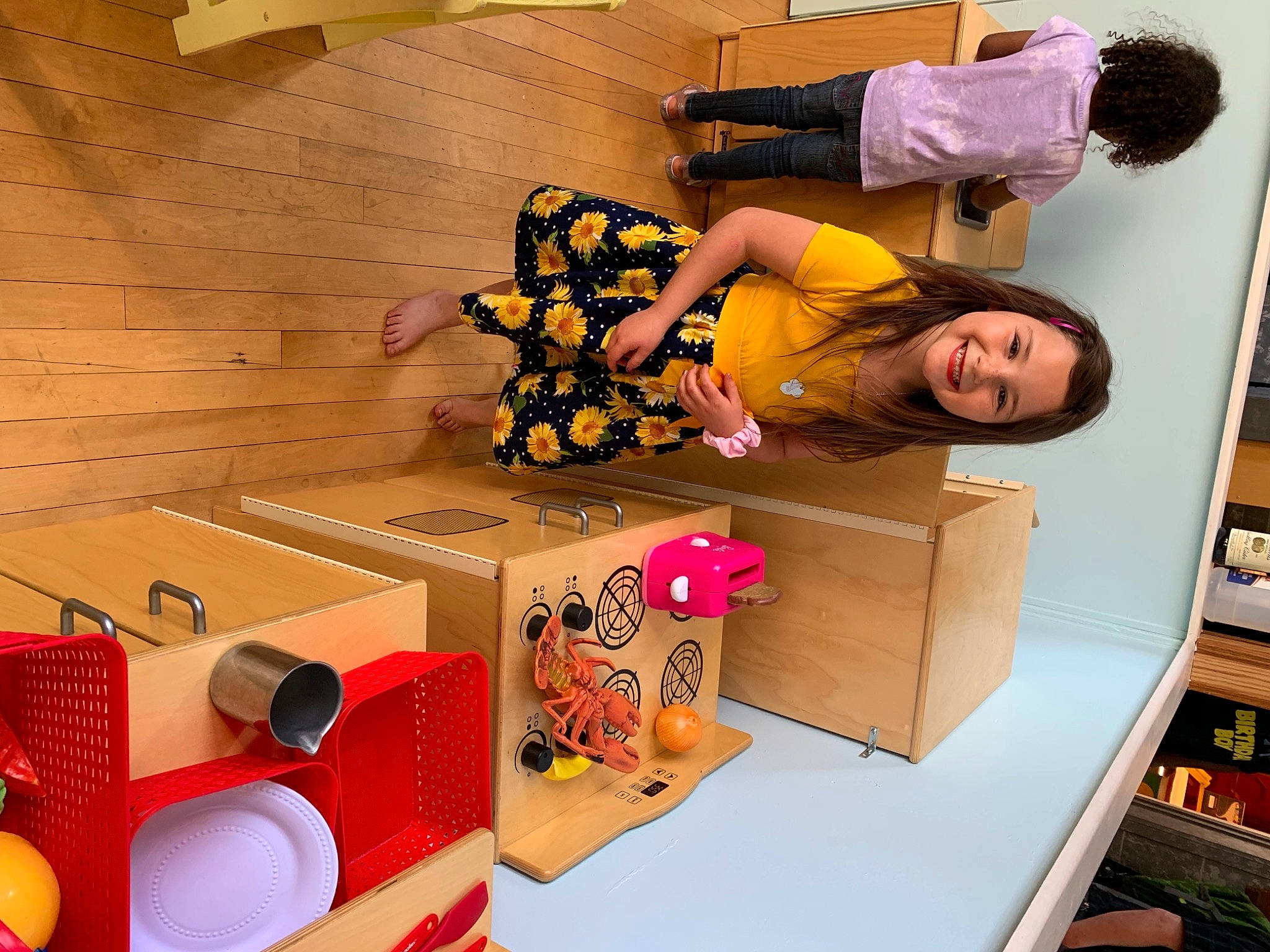 Shailenah is registered to the contest to win money with this photo: audio_equipment, bookcase, box, cardboard, carton, child, eyewear, fashion_design, flooring, happy, interior_design, joy, magenta, person, photograph, pink, room, shelving, shipping_box, smile