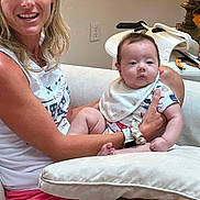 Dylan joined the competition — help win amazing prizes! woman, baby, child, person, indoor, couch, clothing, bib, table, lamp, skin, smile, hair, sitting, holding, relaxed, furniture, casual, home, family