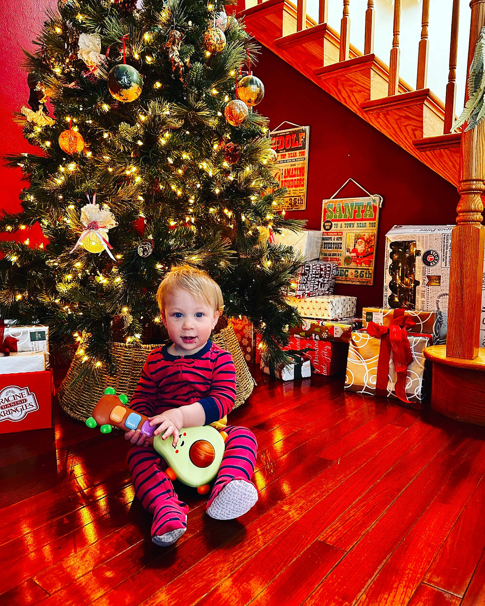 Orin is registered to the contest to win money with this photo: baby_toddler_clothing, building, christmas_decoration, christmas_ornament, christmas_tree, conifer, event, flooring, fun, happy, hardwood, holiday, holiday_ornament, ornament, person, plant, room, smile, snapshot, toddler