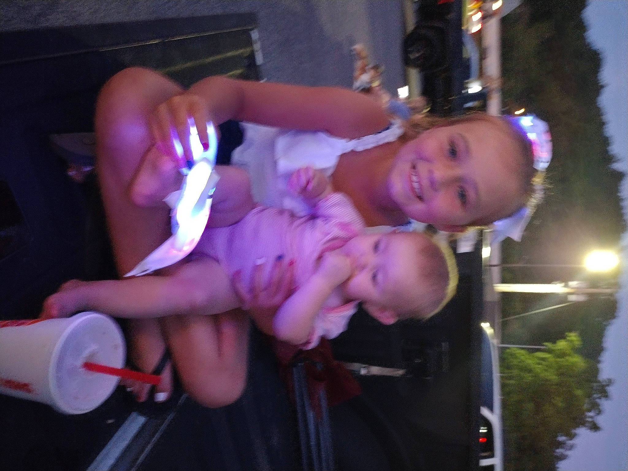 Chloe is registered to the contest to win money with this photo: arm, baby_toddler_clothing, event, finger, fun, happy, human_leg, joy, lap, light, magenta, person, pink, purple, sky, smile, street_light, thigh, thumb, toddler