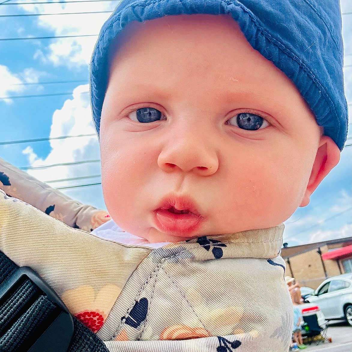 Harrison is registered to the contest to win money with this photo: baby, baseballcap, cap, car, city, clothing, face, hat, head, machine, nature, outdoors, person, photography, portrait, road, sky, transportation, vehicle, wheel