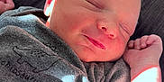 Maverick is registered to the contest to win money with this photo: baby, child, closeup, cozy, cute, dinosaur_print, face, hand, indoors, infant, newborn, onesie, pacifier, peaceful, portrait, resting, sleeping, soft_light, sunlight, tiny