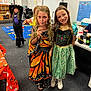 child, children, costume, dress, classroom, lollipop, smile, girl, playful, fun, celebration, holiday, indoor, carpet, table, chair, poster, drawing, friendship, halloween