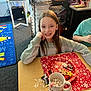 Delayni joined the competition — help win amazing prizes! child, smiling, long_hair, table, hot_chocolate, marshmallows, mug, plate, candy_canes, cookies, classroom, carpet, mirror, furniture, sweatshirt, holiday_theme, desk, writing, stationery, happy