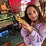 child, girl, lizard, bearded_dragon, purple_jacket, smile, indoor, television, bookshelf, carpet, pet, living_room, animal, person, furniture, reptile, happy, home, long_hair, cozy