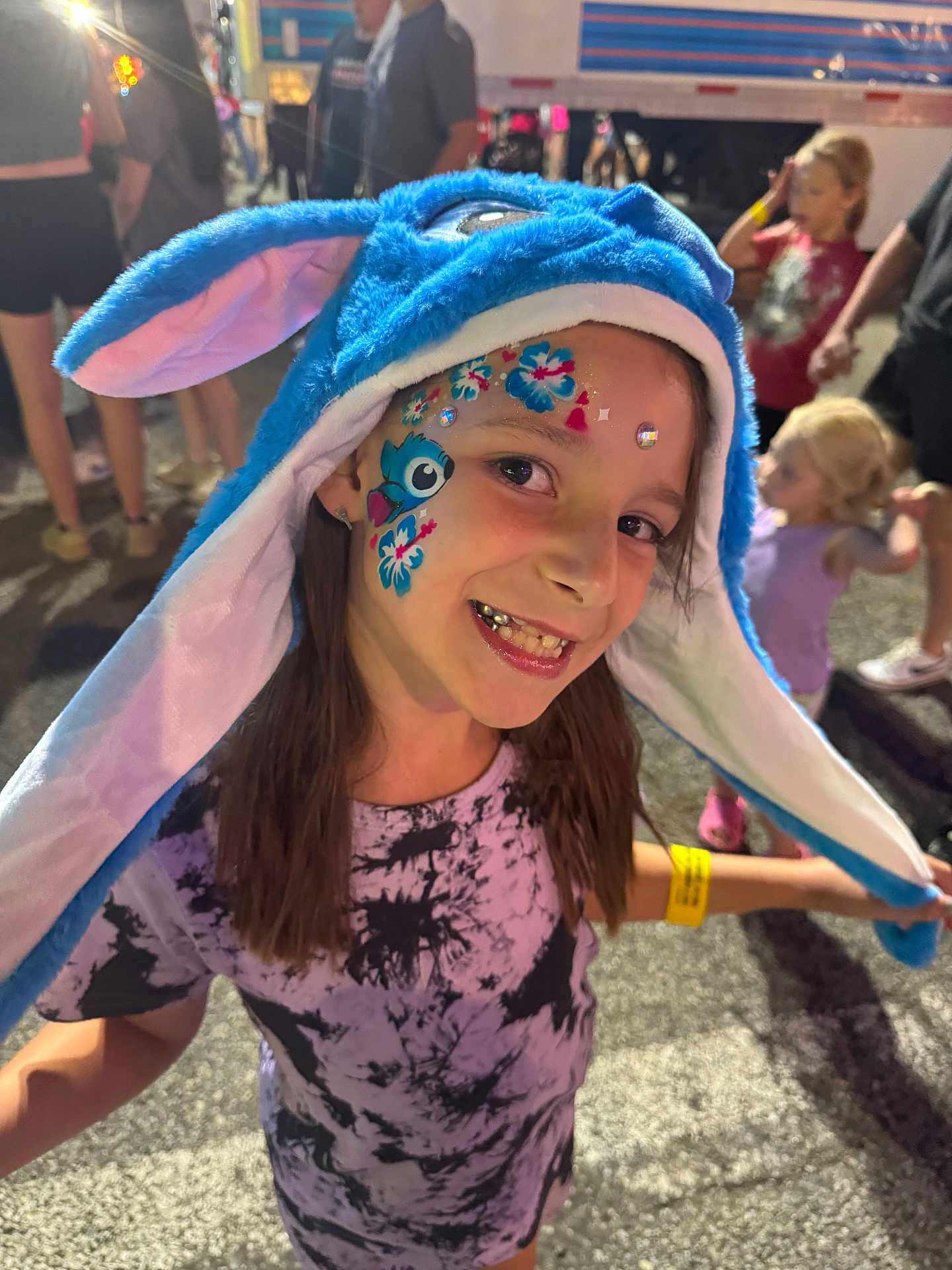 Delayni joined the competition — help win amazing prizes! child, girl, face_paint, blue_hat, costume, smiling, crowd, outdoor, evening, festival, event, people, tshirt, purple_tshirt, happy, portrait, fun, celebration, long_hair, wristband
