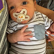 Thomas joined the competition — help win amazing prizes! baby, pacifier, striped_onesie, hand, nails, pocket, face, closeup, infant, person, holding, cute, curious, indoor, skin, eyes, fingers, clothing, adult_hand, comfort