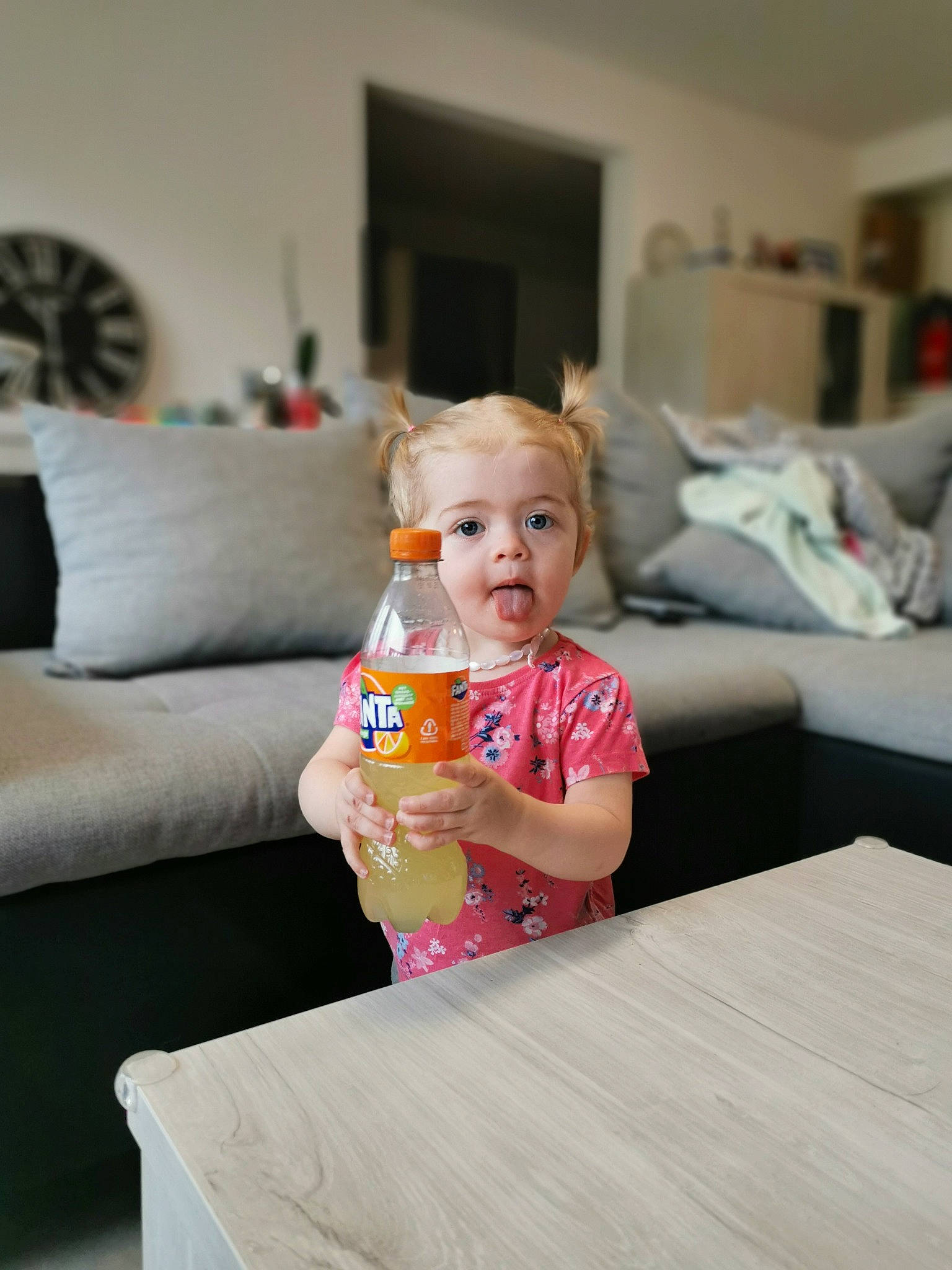 Paulyne participe au concours pour gagner de l'argent avec cette photo : baby, baby_toddler_clothing, bottle, child, comfort, couch, event, eye, flooring, fun, happy, hardwood, leisure, living_room, person, picture_frame, room, sitting, table, toddler
