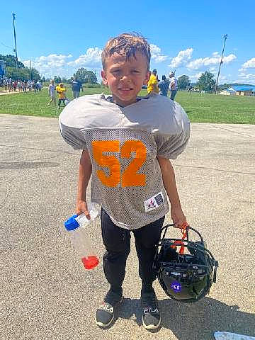 Landon is registered to the contest to win money with this photo: asphalt, automotive_tire, bag, cloud, electric_blue, fun, grass, helmet, landscape, leisure, luggage_and_bags, natural_environment, person, personal_protective_equipment, recreation, shorts, sky, summer, t_shirt, travel