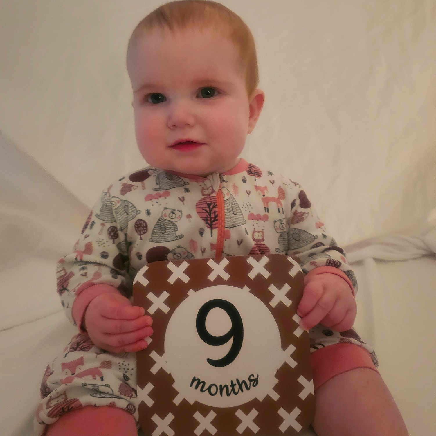 Liliauna joined the competition — help win amazing prizes! 9_months, animal_print, baby, child, cute, face, feet, hand, head, indoors, infant, legs, milestone, pajamas, portrait, sign, sitting, smiling, soft_lighting, white_background