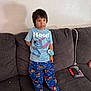Ollie is registered to the contest to win money with this photo: barefoot, boy, cartoon_character, child, colorful_clothing, couch, curly_hair, home, indoor, living_room, pajamas, photo_collage, relaxed, shadow, shirt, smiling, standing, tablet, toy, wall_art