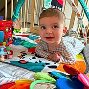 Lawton joined the competition — help win amazing prizes! baby, infant, play_mat, toy, colorful, indoor, wooden_gate, smiling, happy, child, clothing, face, eyes, hand, floor, patterned, soft_toys, mirror, curious, crawling