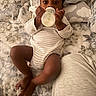 baby, bed, bedroom, blanket, bottle, child, cozy, feeding, indoor, infant, lying_down, milk, onesie, photography, pillow, portrait, relaxed, sitting, striped_clothing, wide_eyes